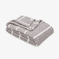 A folded gray knit blanket with white stripes, displayed on a clean white background.