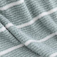 A close-up of a plush, textured fabric with horizontal white stripes on a muted sage green background.