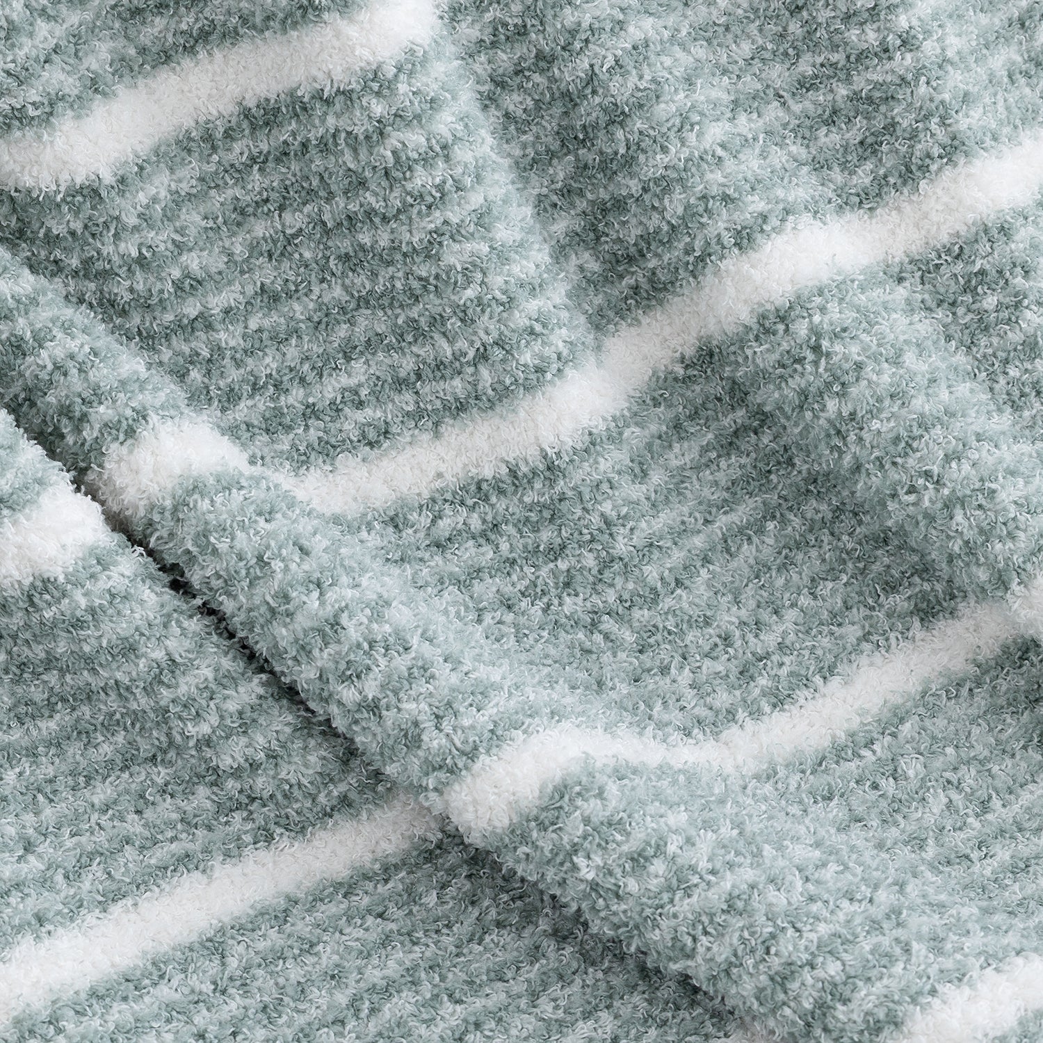 A close-up of a plush, textured fabric with horizontal white stripes on a muted sage green background.