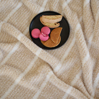 A plate of desserts set on a neutral striped retro plush throw.