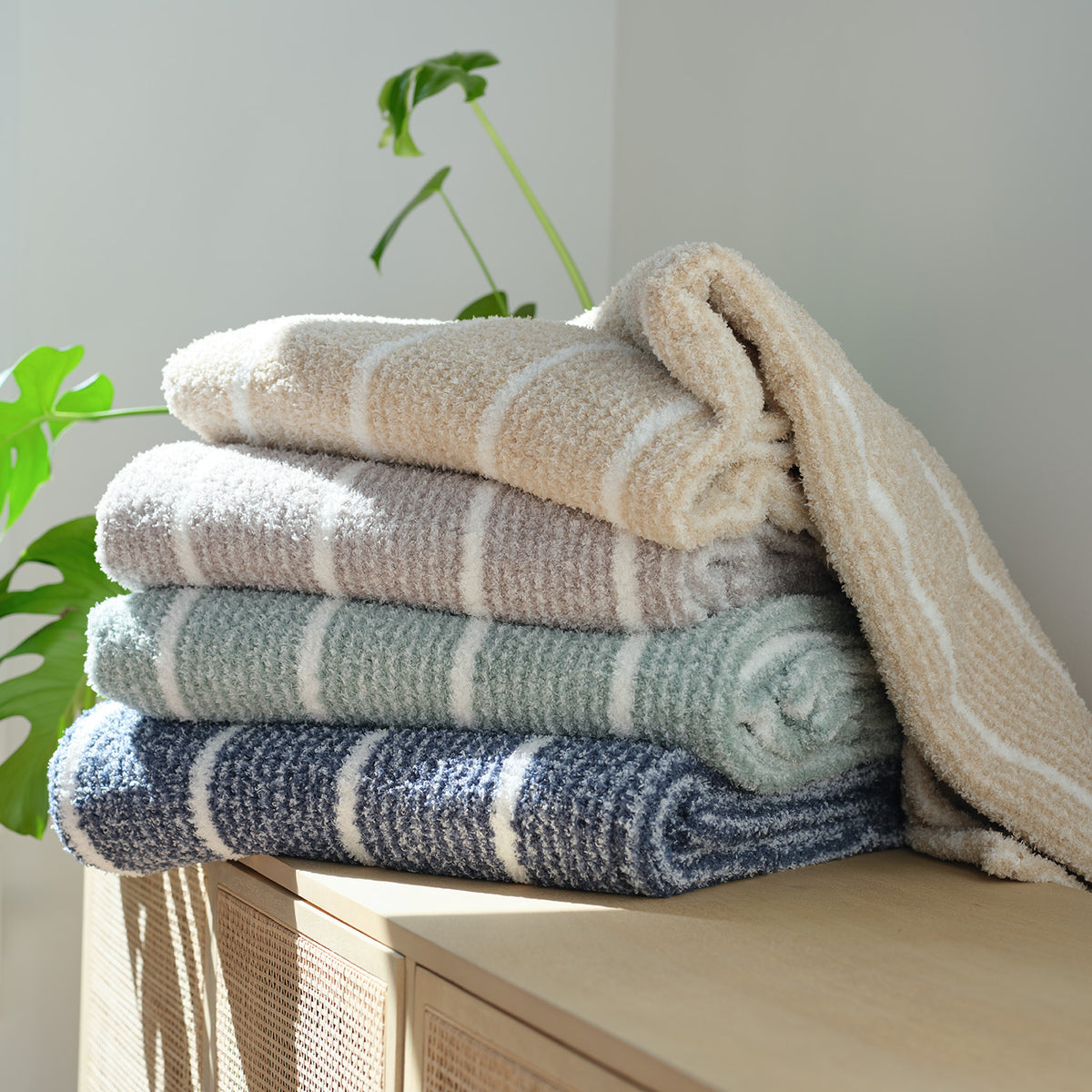 A stack of striped Retro Plush Throws stacked on a wooden console table.