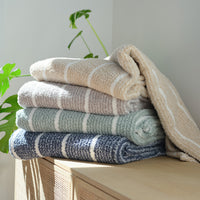 A stack of striped Retro Plush Throws stacked on a wooden console table.