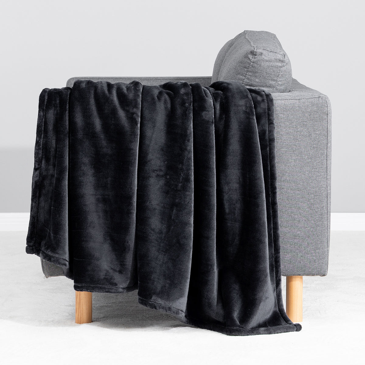 Premium VelvetLoft® Throw in Black, draped over the arm of a gray sofa, close view
