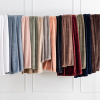 Premium VelvetLoft® Throws in assorted Colors hanging side by side on a rail against a white paneled wall