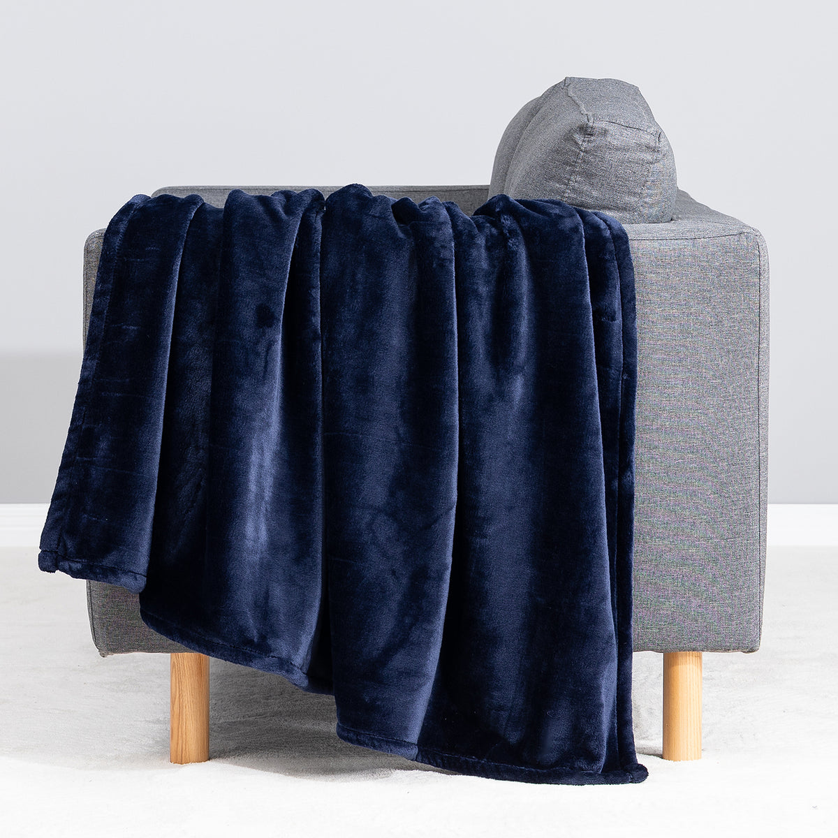 Premium VelvetLoft® Throw in Midnight Blue, draped over the arm of a gray sofa, close view