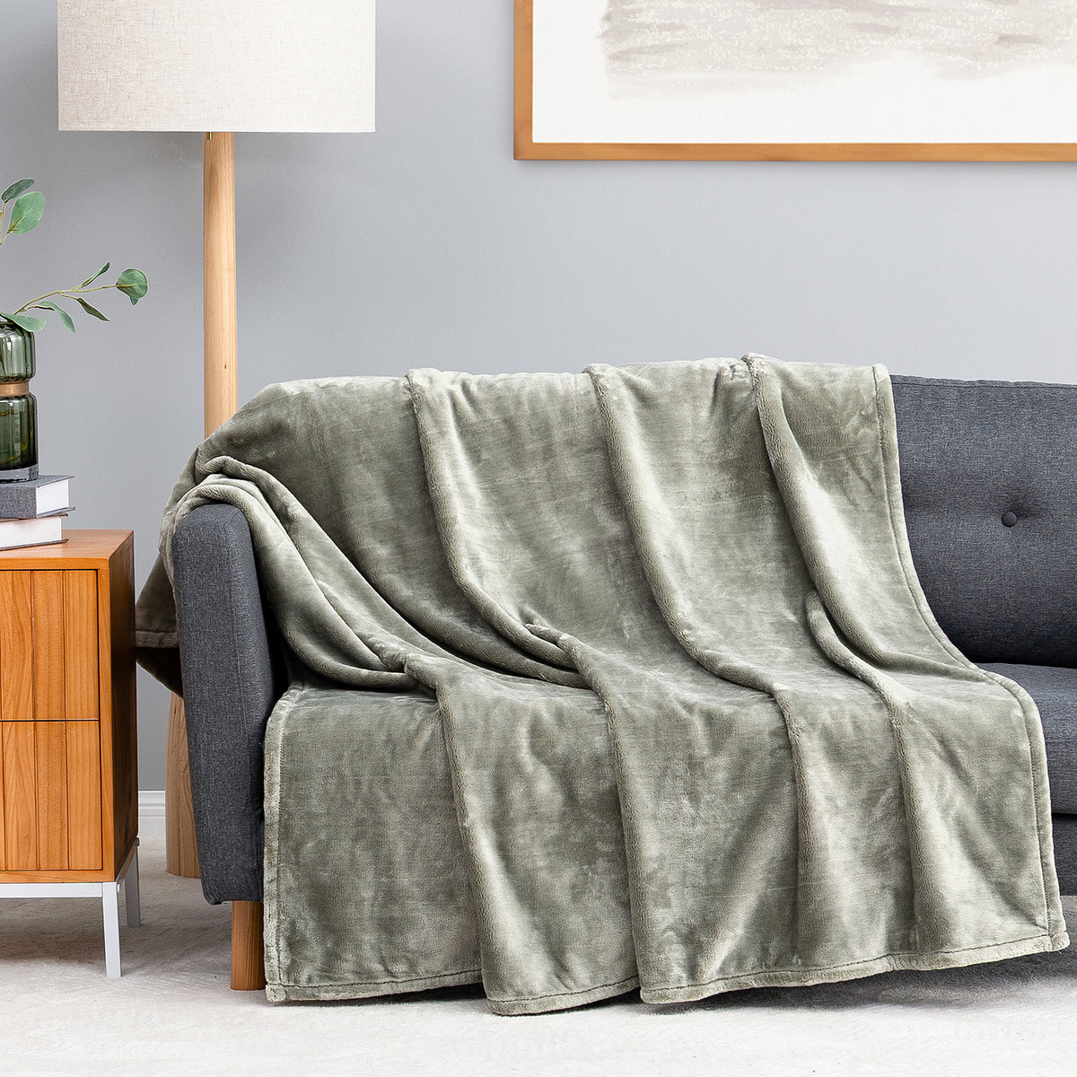 Premium VelvetLoft® Throw in Olive Shadow, draped over a gray sofa in a living room