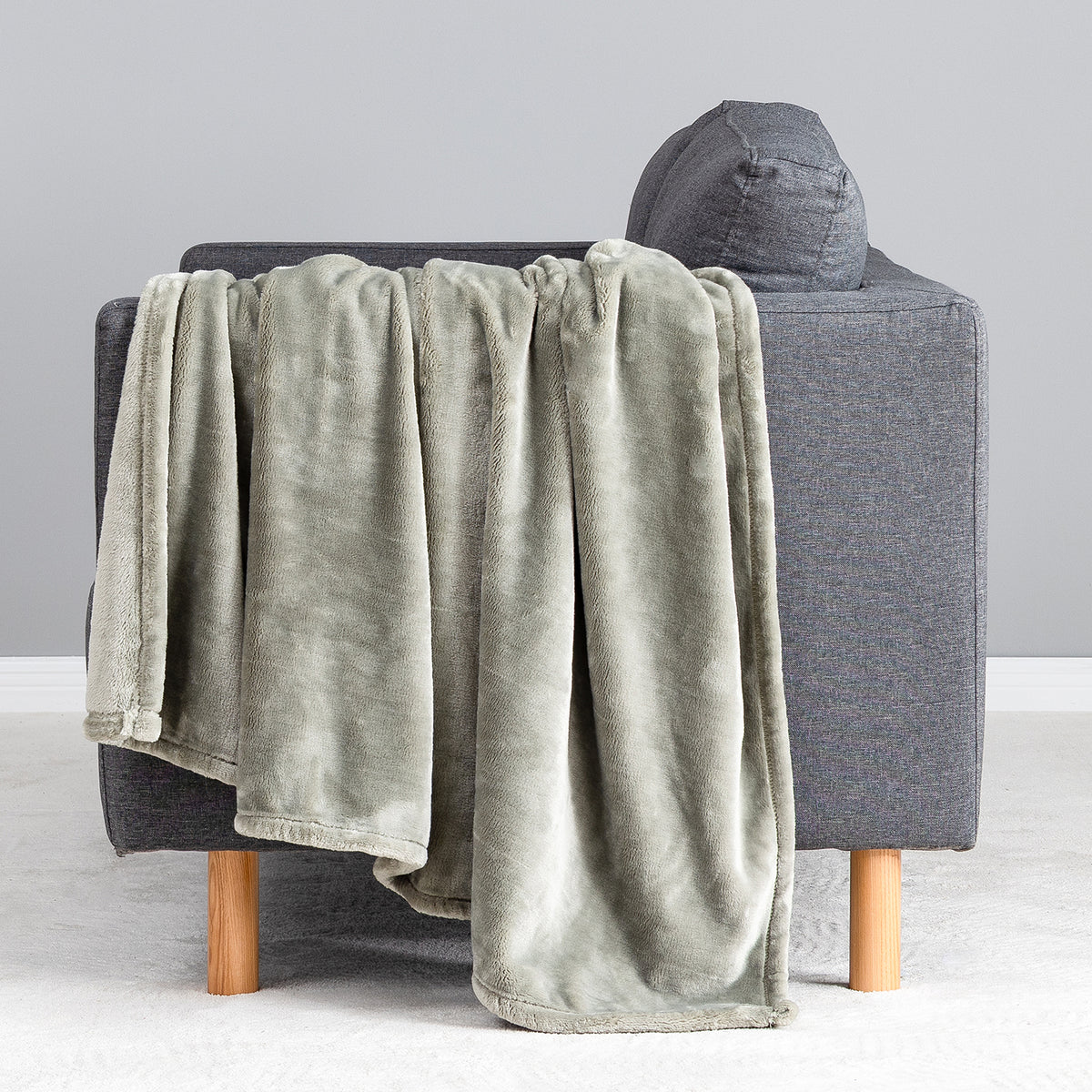 Premium VelvetLoft® Throw in Olive Shadow, draped over the arm of a gray sofa, close view