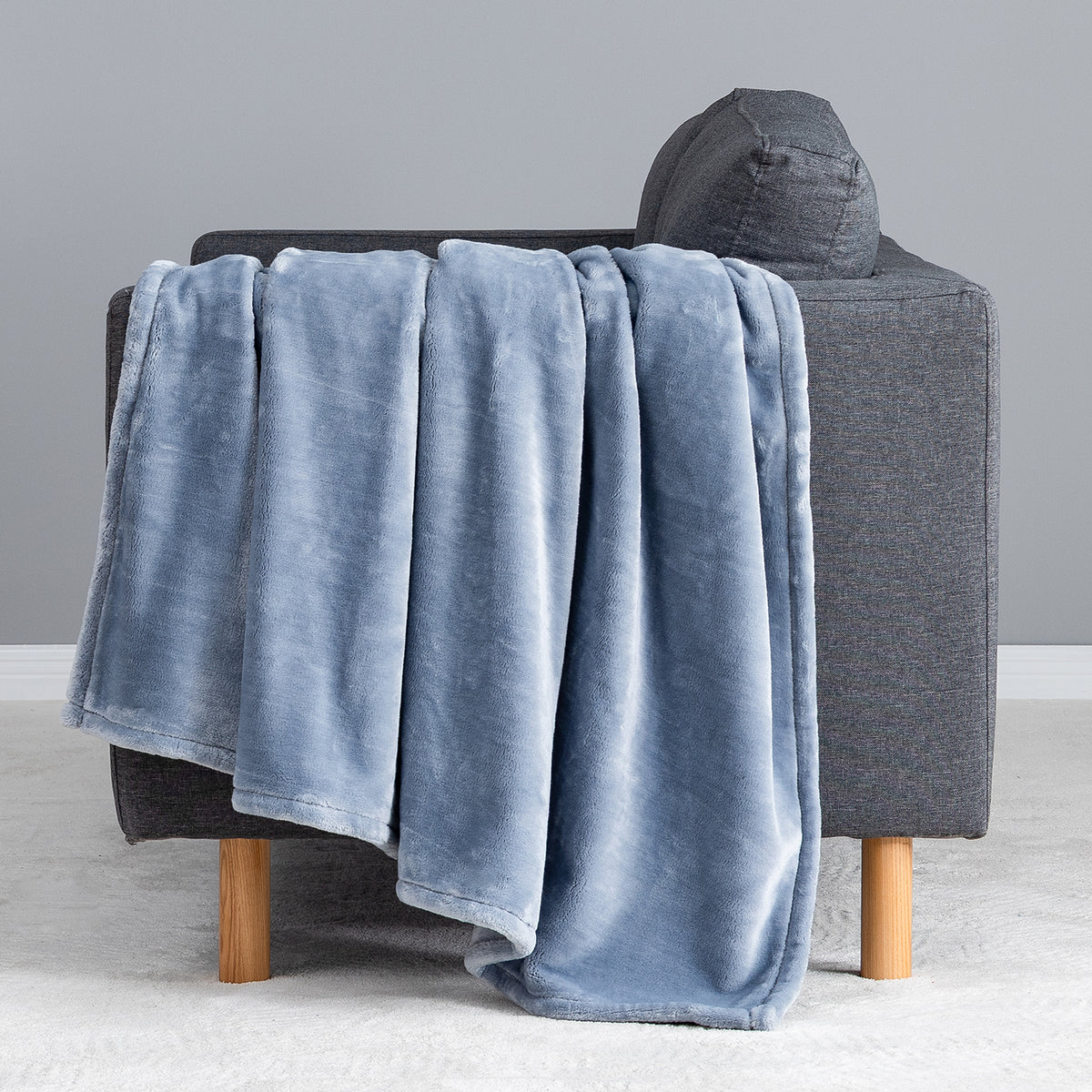 Premium VelvetLoft® Throw in Polar Blue, draped over the arm of a gray sofa, close view