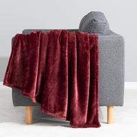 Premium VelvetLoft® Throw in Roanoke Red, draped over the arm of a gray sofa, close view