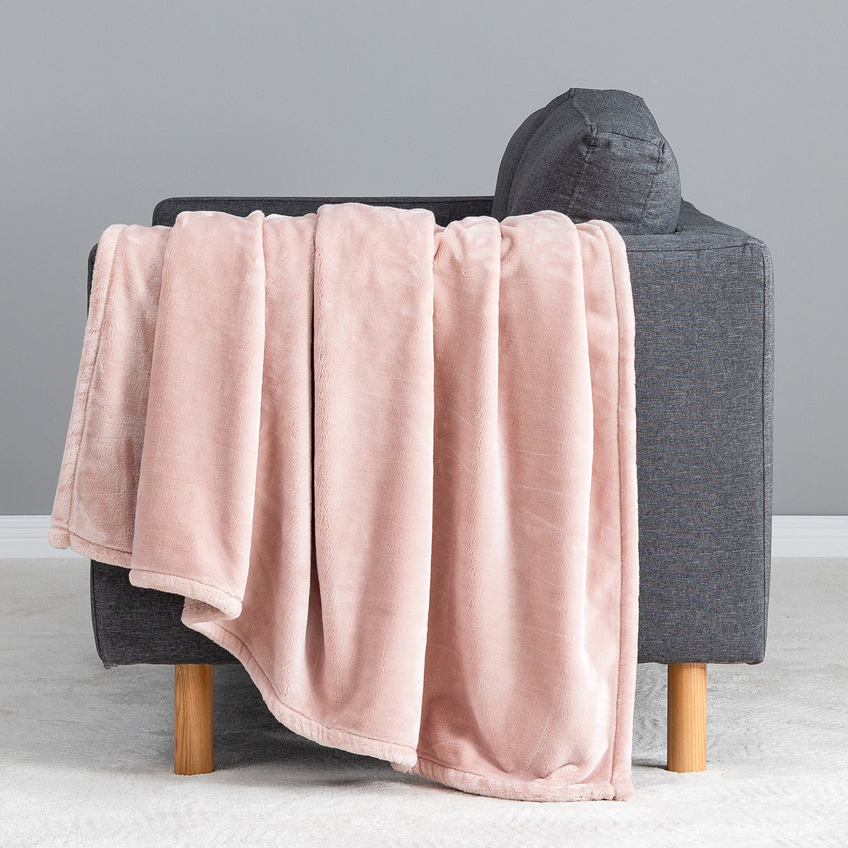 Premium VelvetLoft® Throw in Rose Smoke, draped over the arm of a gray sofa, close view