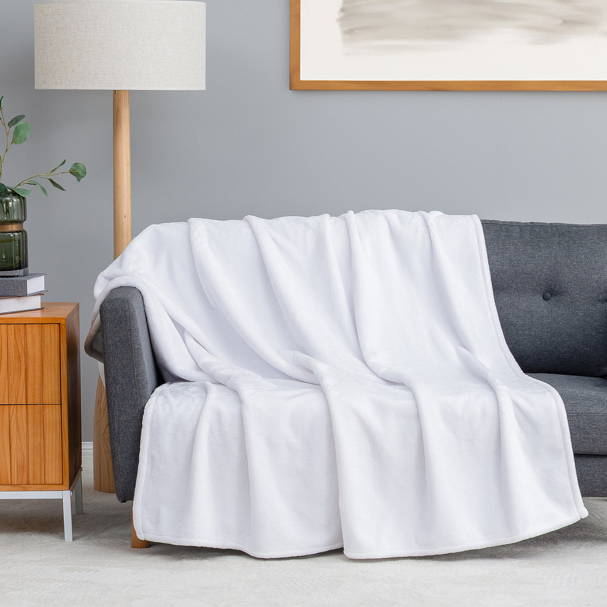 Premium VelvetLoft® Throw in True White, draped over a gray sofa in a living room