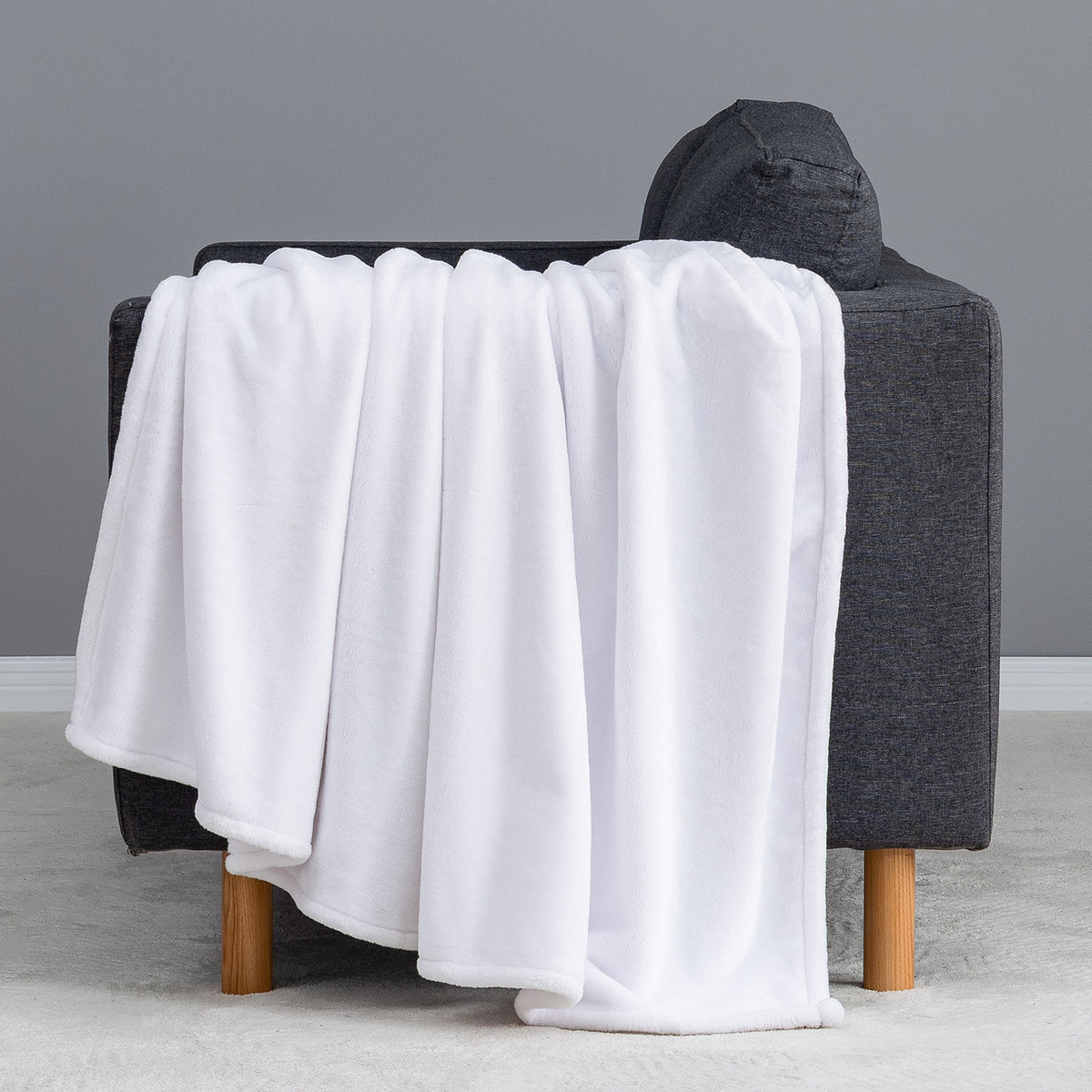 Premium VelvetLoft® Throw in True White, draped over the arm of a gray sofa, close view