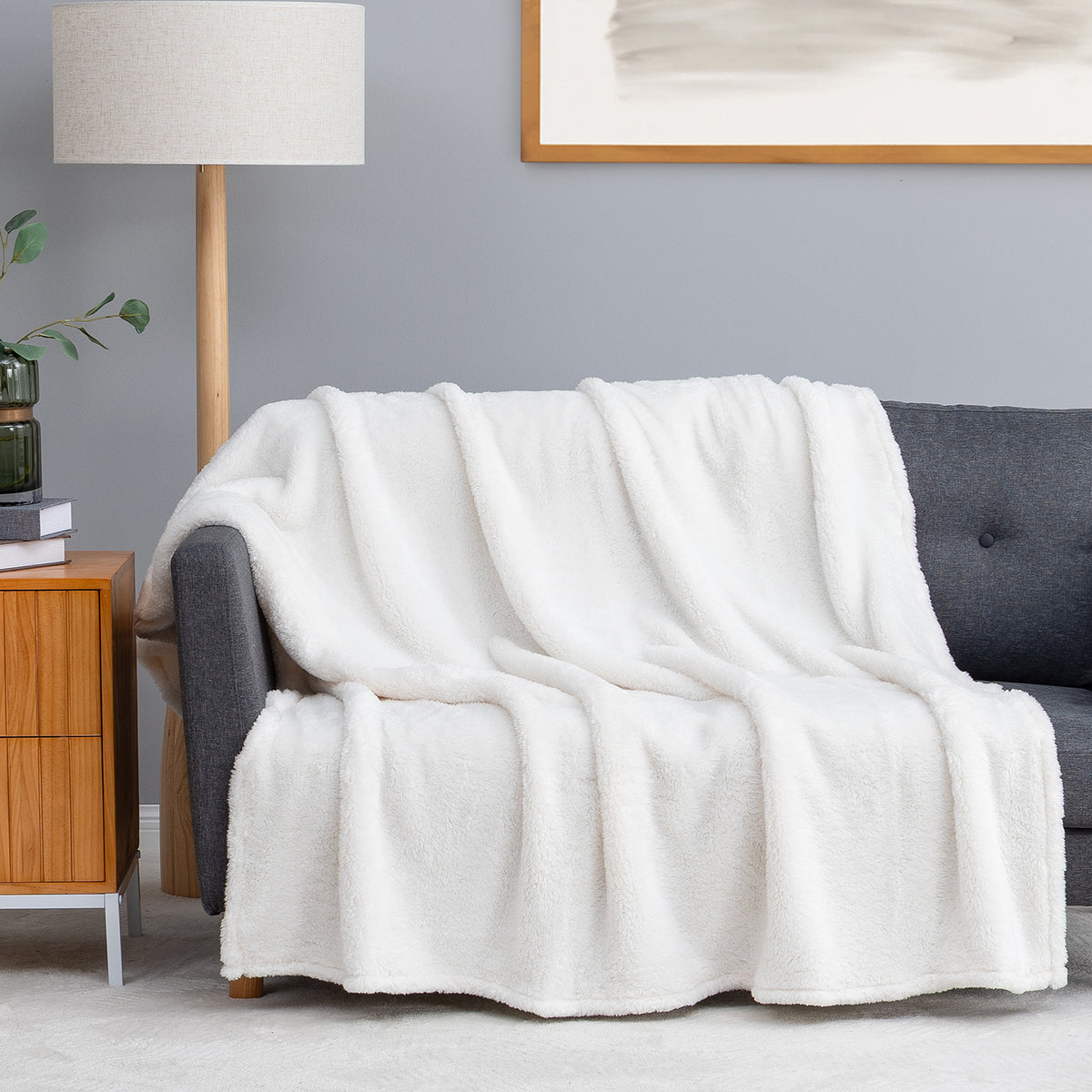 Premium Extra-Fluffy™ Throw in Cream draped over a gray sofa in a living room
