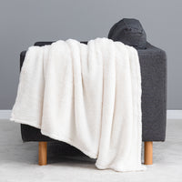 Premium Extra-Fluffy™ Throw in Cream draped over the arm of a gray sofa, close view