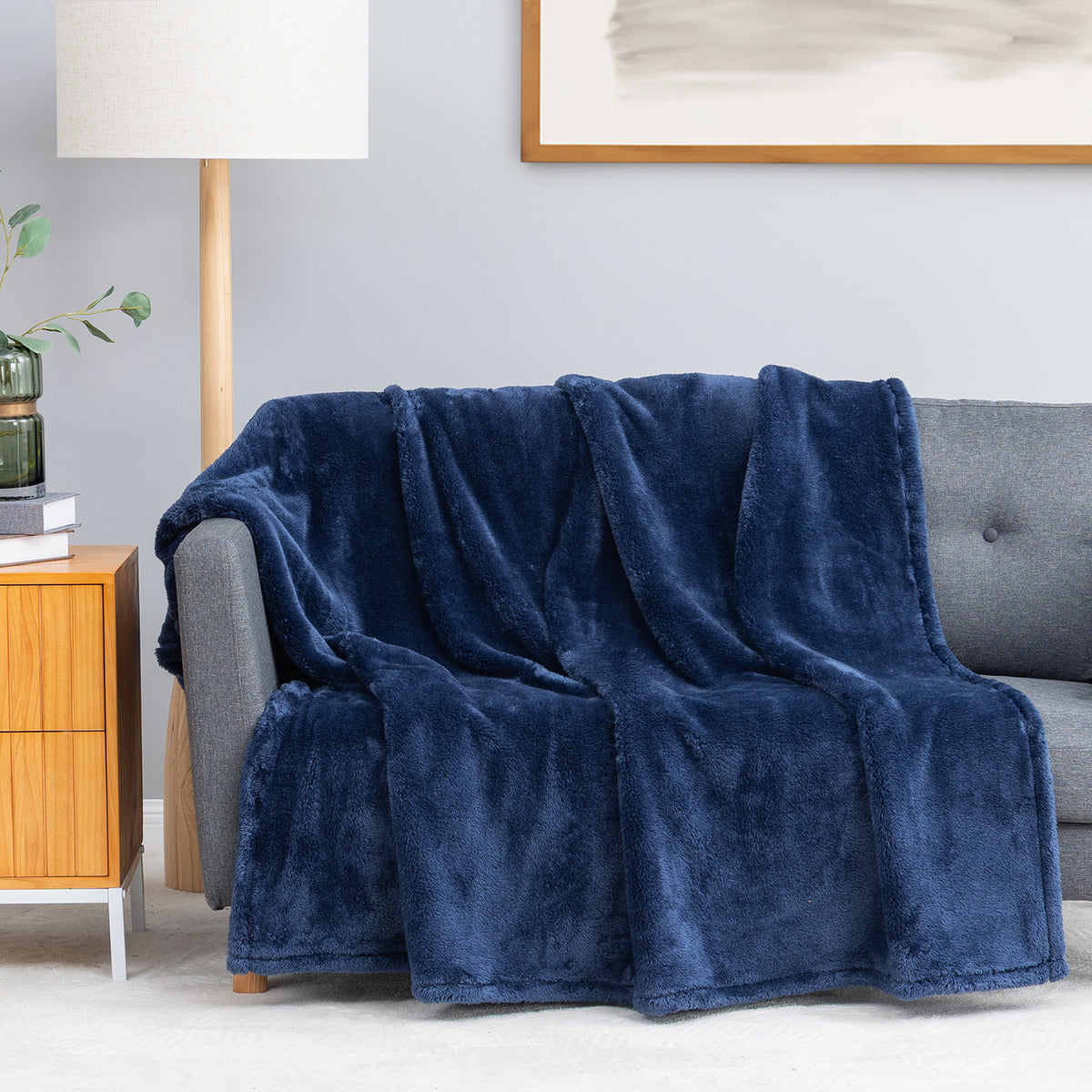 Premium Extra-Fluffy™ Throw in Dress Blue draped over a gray sofa in a living room