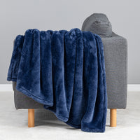 Premium Extra-Fluffy™ Throw in Dress Blue draped over the arm of a gray sofa, close view