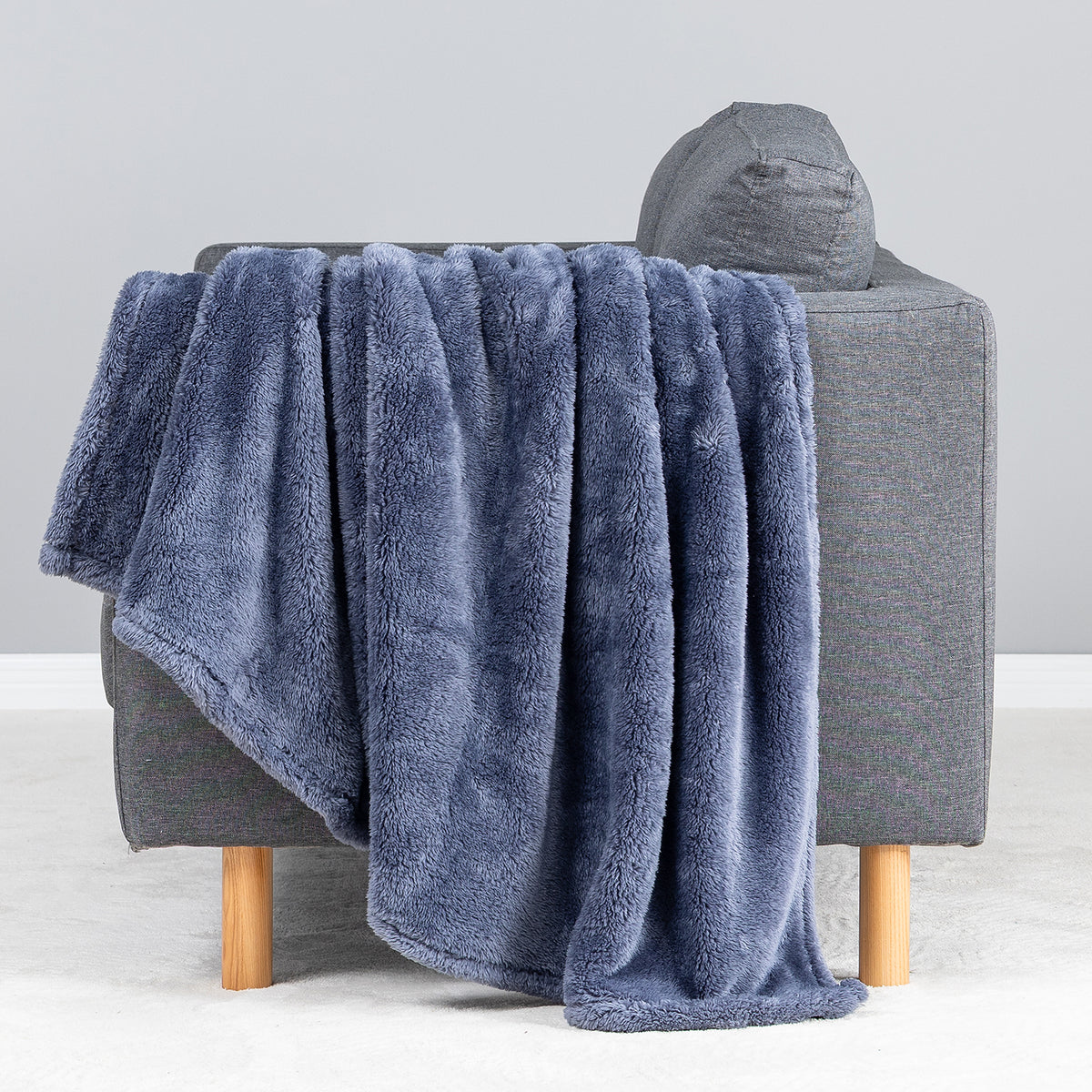 Premium Extra-Fluffy™ Throw in Galaxy Blue draped over the arm of a gray sofa, close view