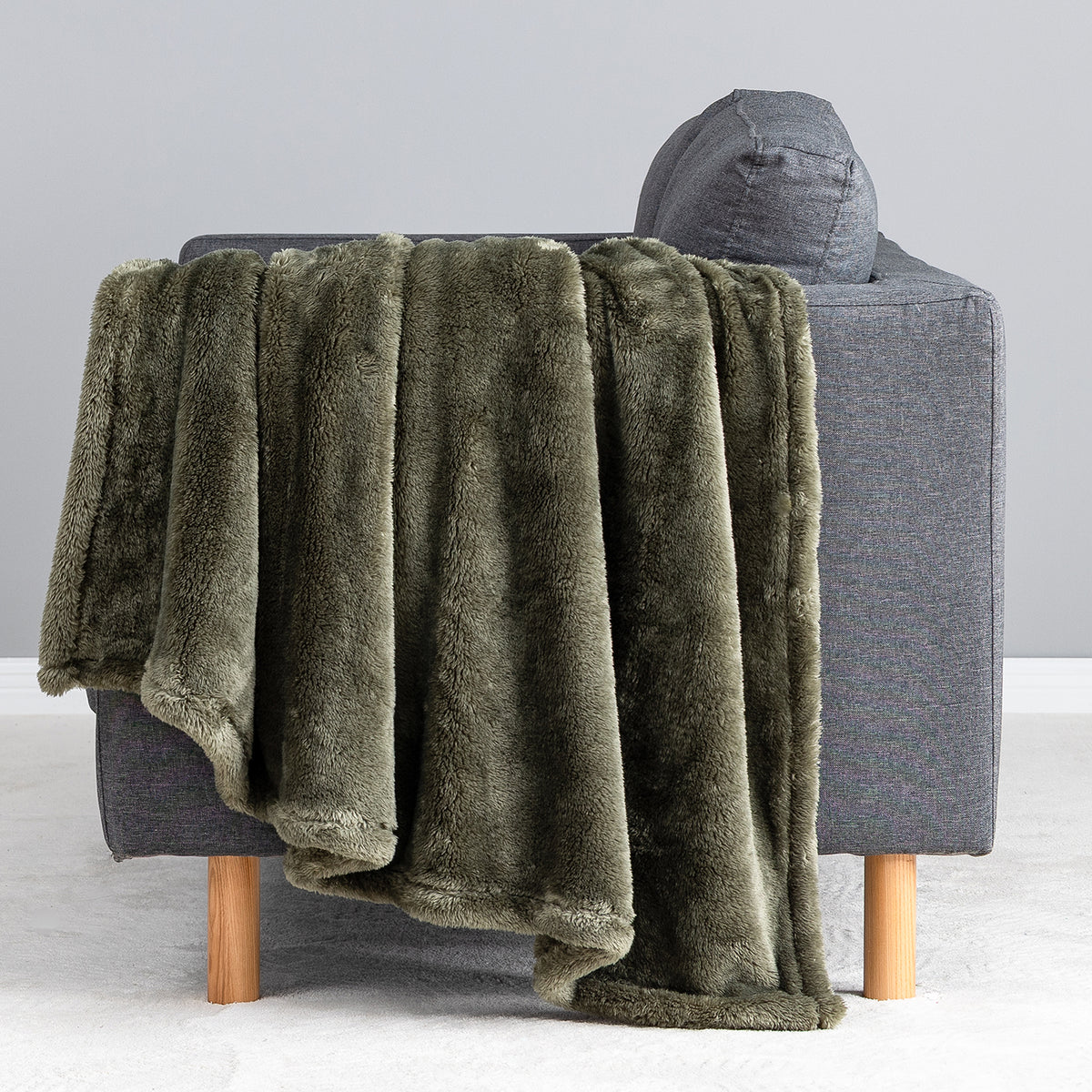 Premium Extra-Fluffy™ Throw in Ivy draped over the arm of a gray sofa, close view