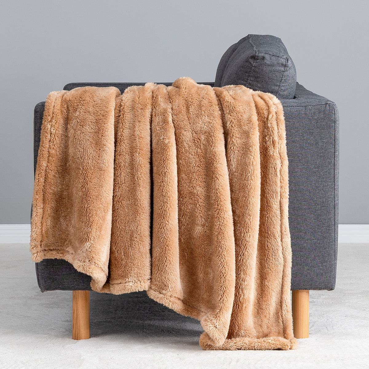 Premium Extra-Fluffy™ Throw in Prosecco draped over the arm of a gray sofa, close view