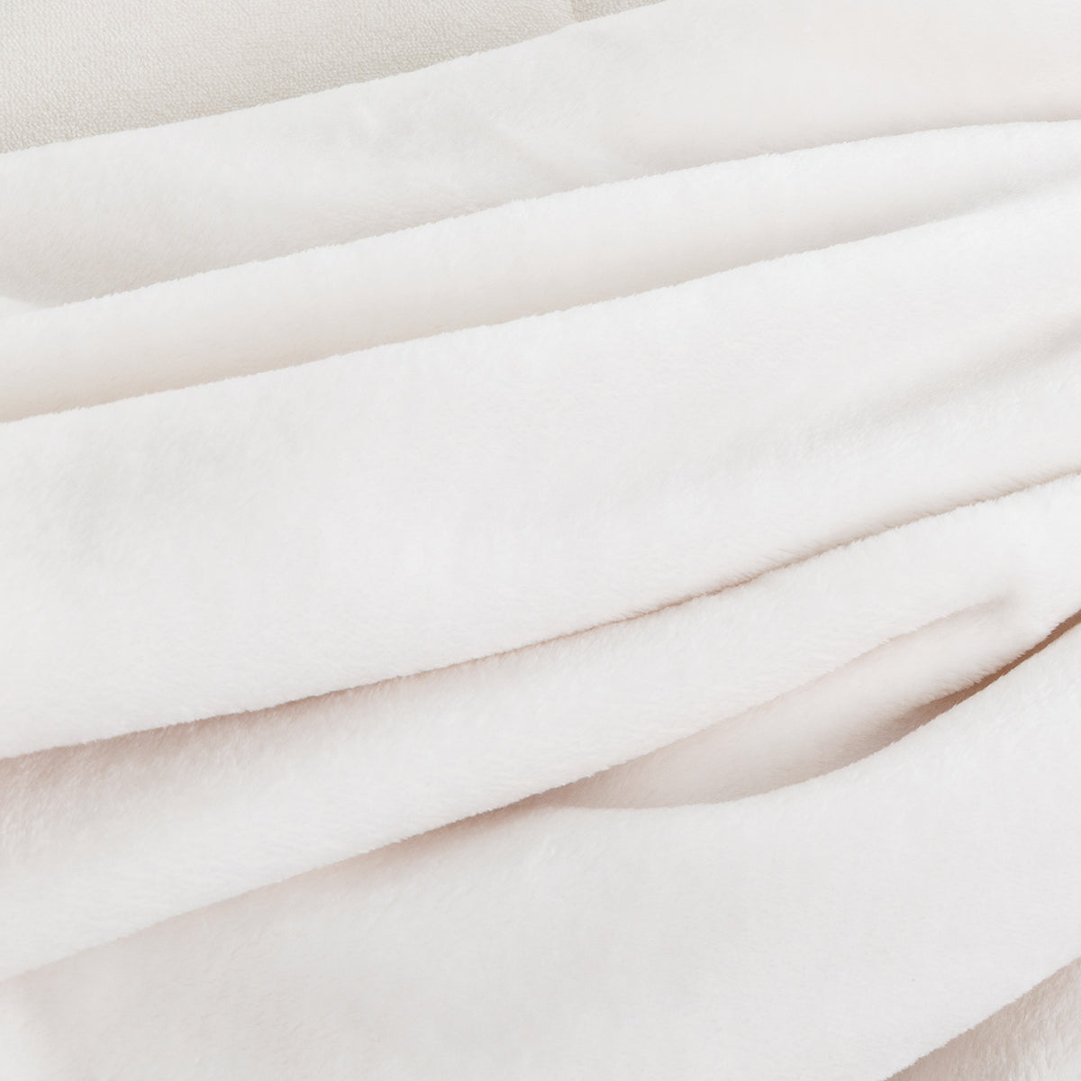 A close-up of soft, draped fabric in a very light warm off-white or blush tone, showing the texture and folds of the material.