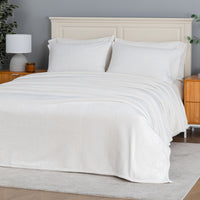 Premium VelvetLoft® Blanket in Cream on a made bed, angled view