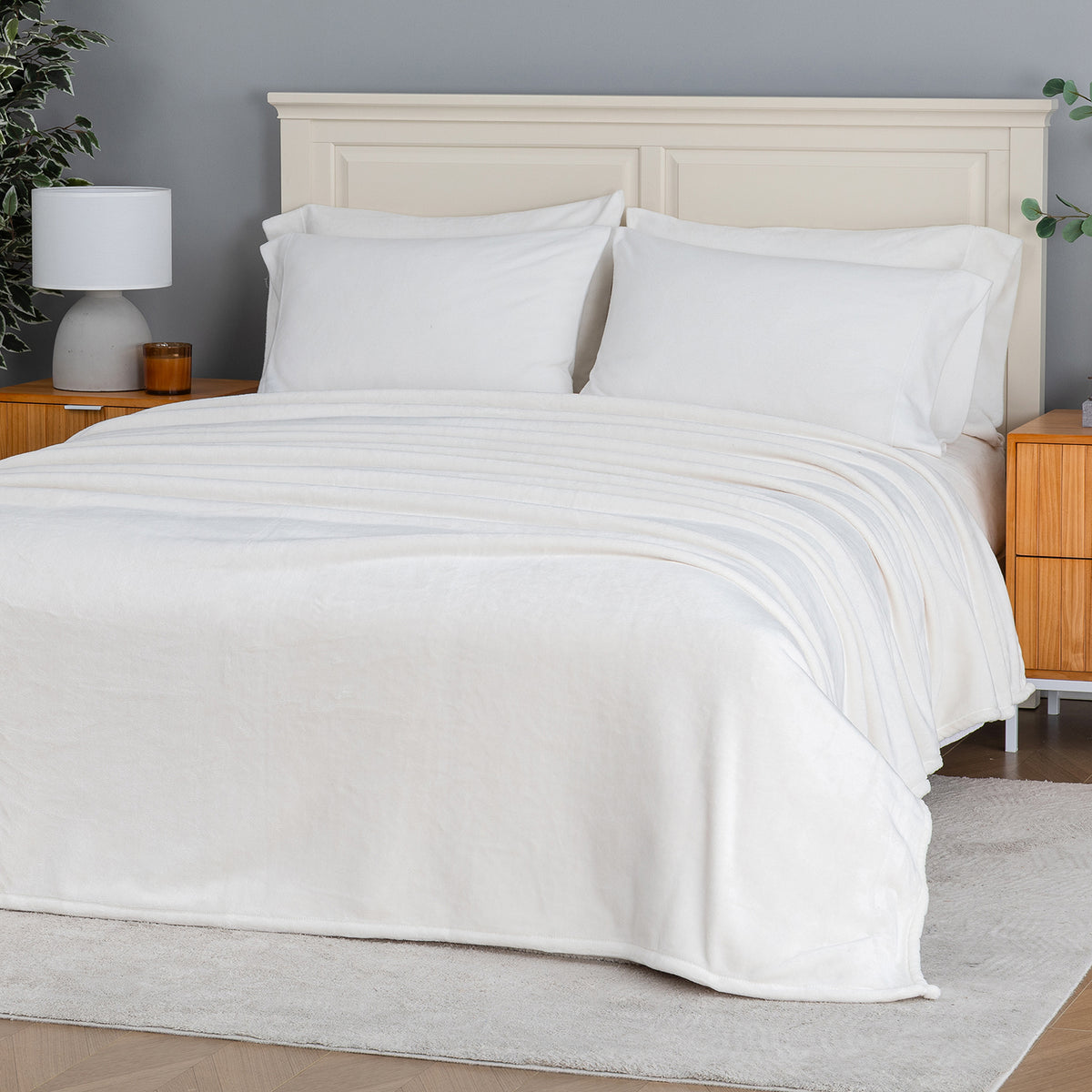 Premium VelvetLoft® Blanket in Cream on a made bed, angled view