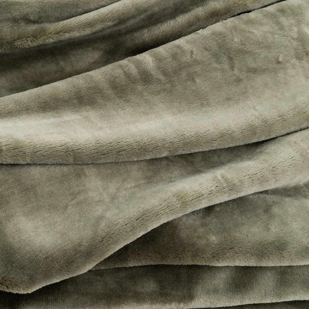 A close-up of draped plush fabric in a muted green color, showing the soft texture and folds of the material.