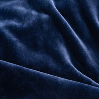A close-up of draped navy blue velvet fabric, showing its soft texture and rich color with gentle folds.