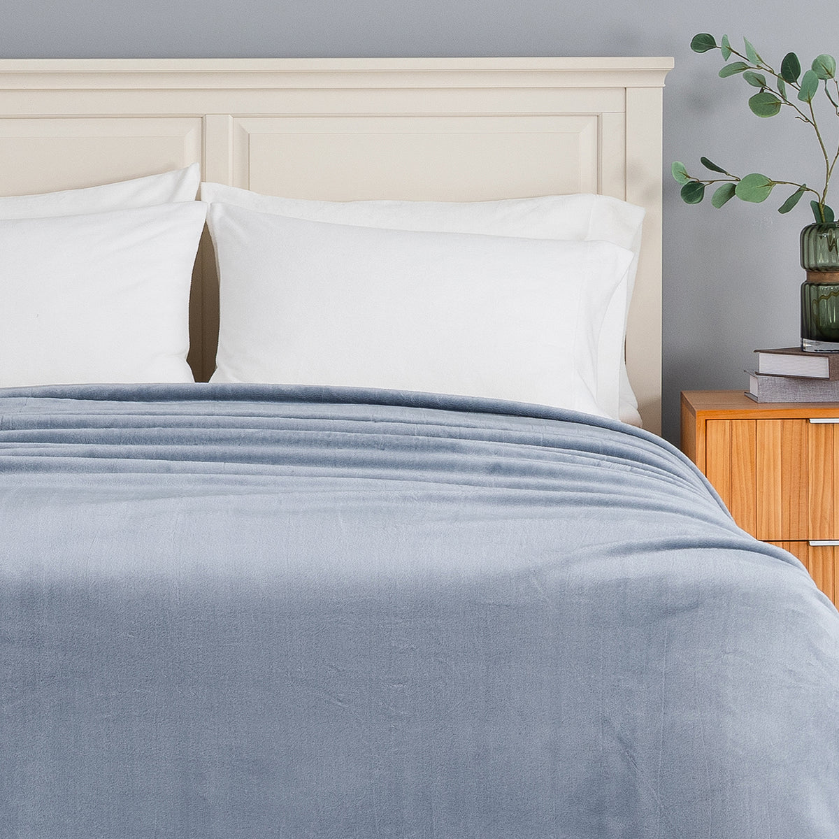 A blue Premium VelvetLoft Blanket draped neatly over a bed.