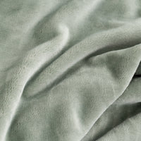 A close-up of soft, plush fabric in a muted sage green color, showing the texture and folds of the material.