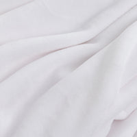 A close-up of soft white fabric with gentle folds and a smooth, slightly plush texture.