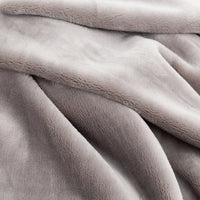 A close-up of a soft, plush throw blanket in a light taupe-gray color, showing its textured fleece fabric and draped folds.
