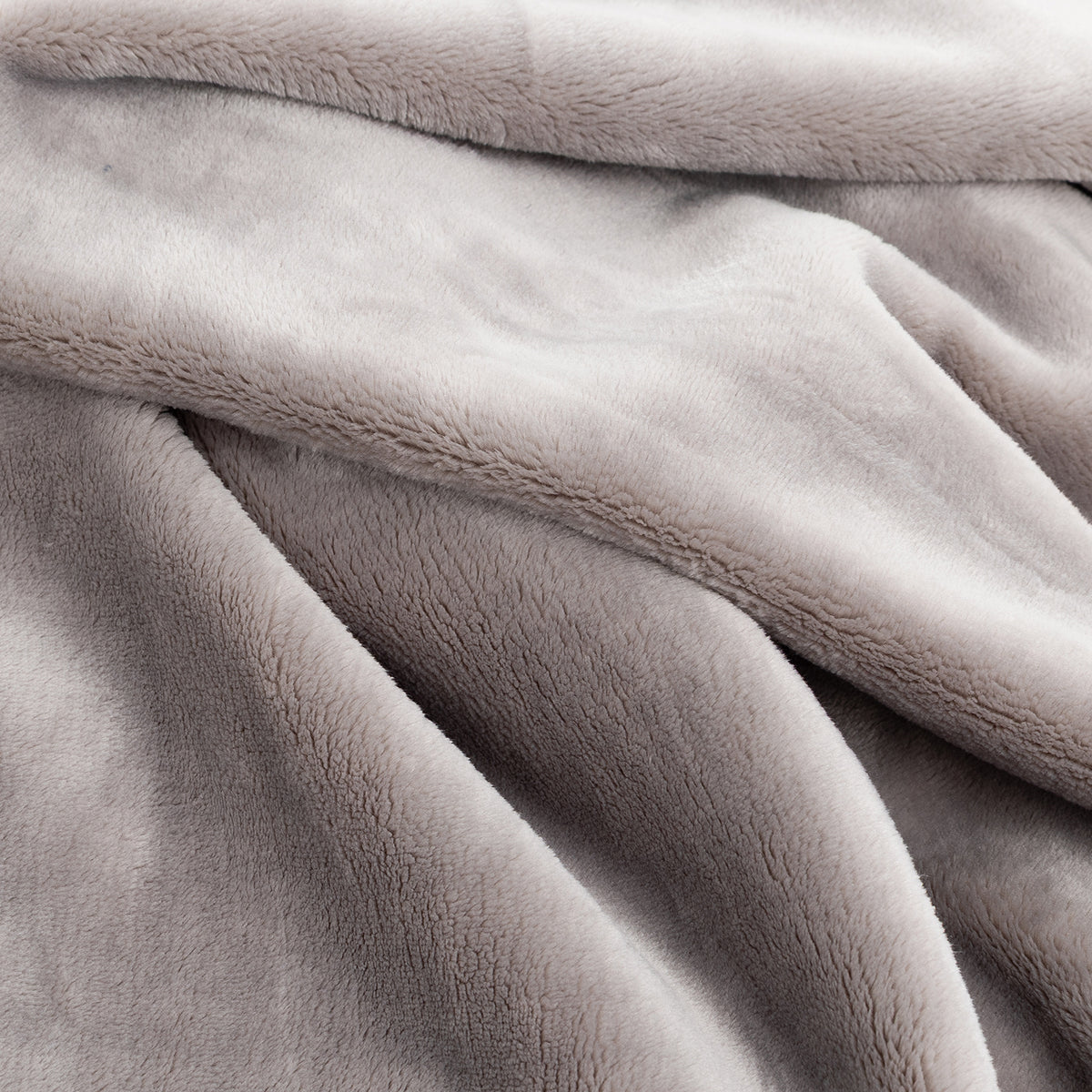 A close-up of a soft, plush throw blanket in a light taupe-gray color, showing its textured fleece fabric and draped folds.