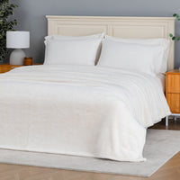 Premium Extra-Fluffy™ Blanket in Cream spread over a made bed, angled view