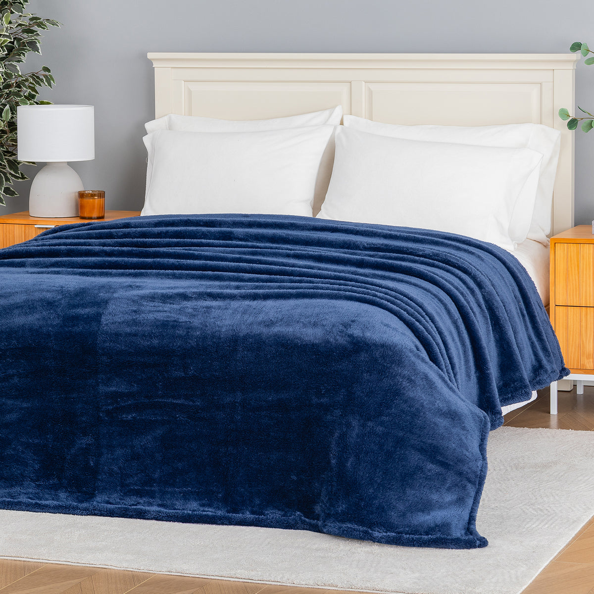 Premium Extra-Fluffy™ Blanket in Dress Blue spread over a made bed, angled view