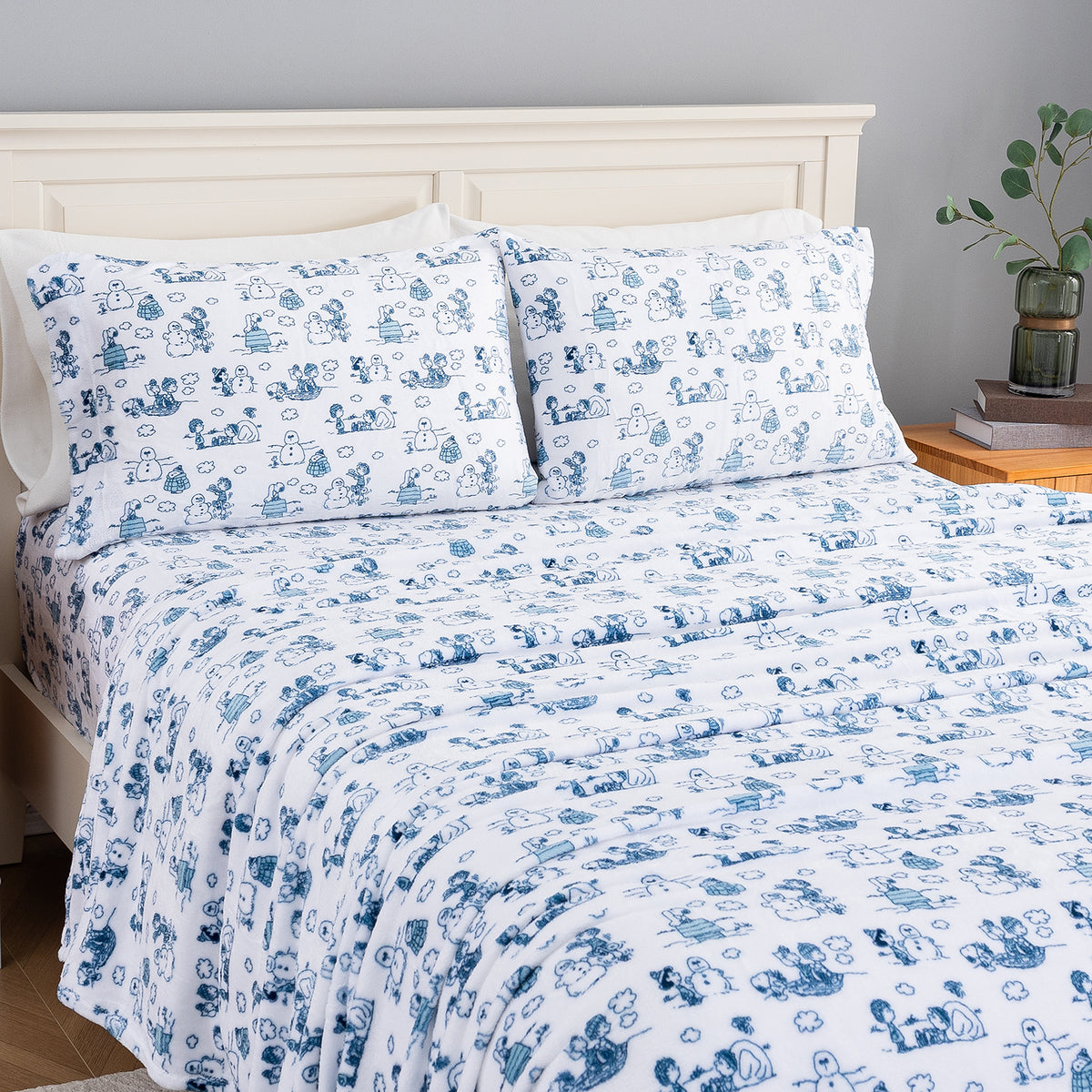 Peanuts white and blue holiday printed VelvetLoft sheet set dressed neatly on a bed.