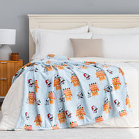 A blue gingerbread holiday Peanuts Printed VelvetLoft Throw draped neatly over a bed.
