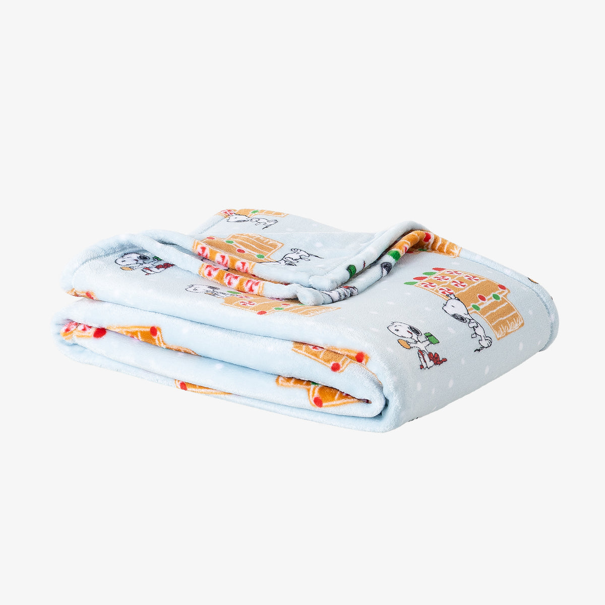 A blue gingerbread holiday Peanuts Printed VelvetLoft Throw folded neatly on a white surface.