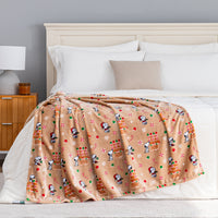 A gingerbread holiday Peanuts Printed VelvetLoft Throw draped neatly over a bed.