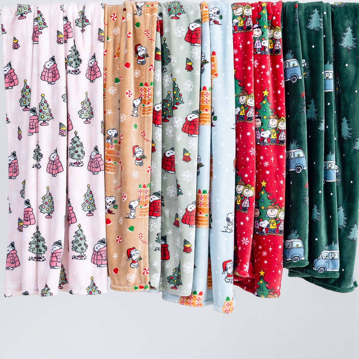 A variety of holiday Peanuts VelvetLoft Throws draped to display their prints.