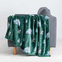A green holiday Peanuts Printed VelvetLoft Throw draped over a grey chair.