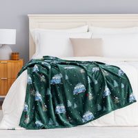 A green holiday Peanuts Printed VelvetLoft Throw draped neatly over a bed.