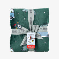 A holiday Peanuts Printed VelvetLoft Throw folded neatly with a ribbon on a white surface.