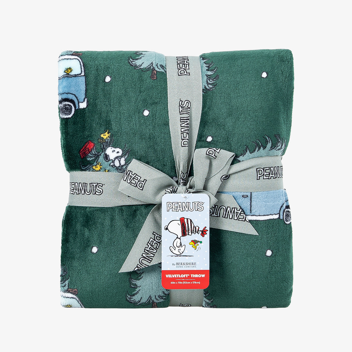 A holiday Peanuts Printed VelvetLoft Throw folded neatly with a ribbon on a white surface.