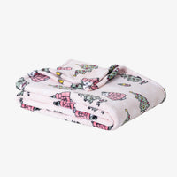 A pink holiday Peanuts Printed VelvetLoft Throw folded neatly on a white surface.
