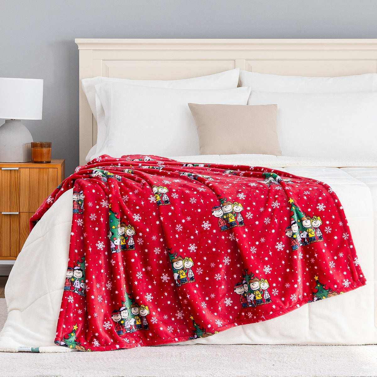 A holiday Peanuts Printed VelvetLoft Throw draped neatly over a bed.