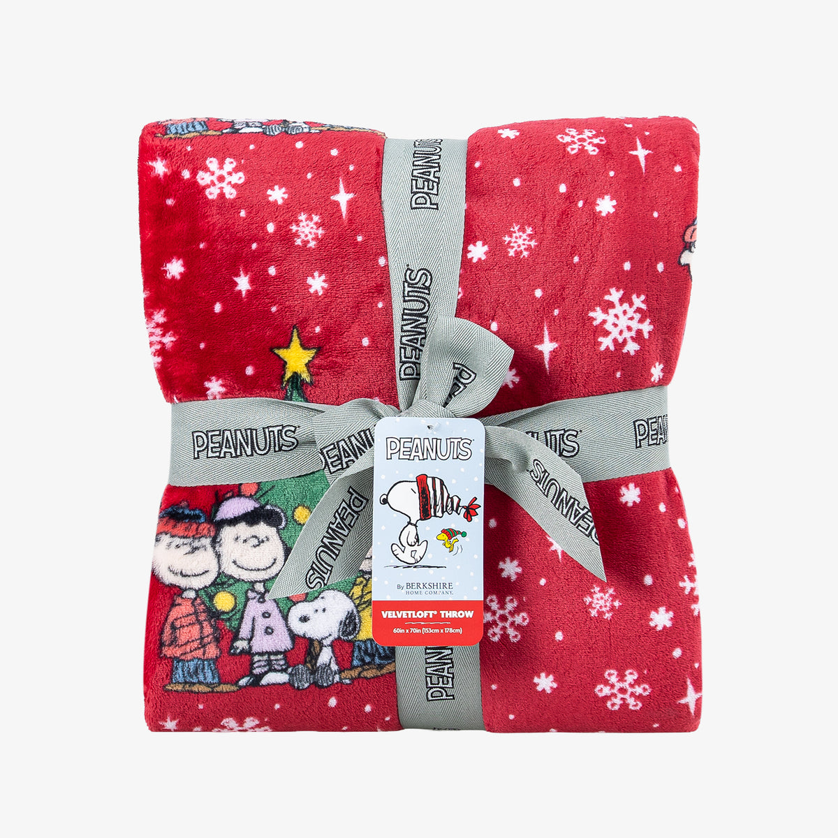 A holiday Peanuts Printed VelvetLoft Throw folded neatly with a ribbon on a white surface.