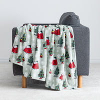 A sage green holiday Peanuts Printed VelvetLoft Throw draped over a grey chair.