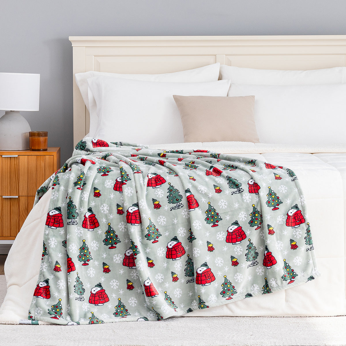 A holiday Peanuts Printed VelvetLoft Throw draped neatly over a bed.