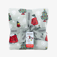 A holiday Peanuts Printed VelvetLoft Throw folded neatly with a ribbon on a white surface.